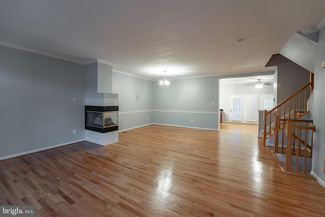 unfurnished living room with ornamental molding, a fireplace, ceiling fan with notable chandelier, and light wood-type flooring