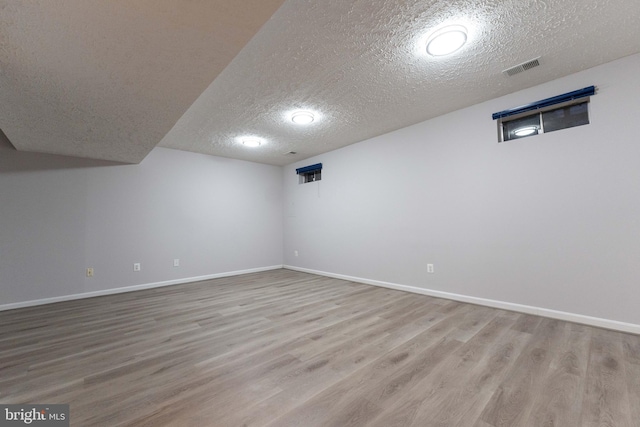 basement with wood-type flooring and a textured ceiling