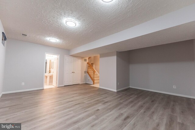 basement featuring wood-type flooring and a textured ceiling