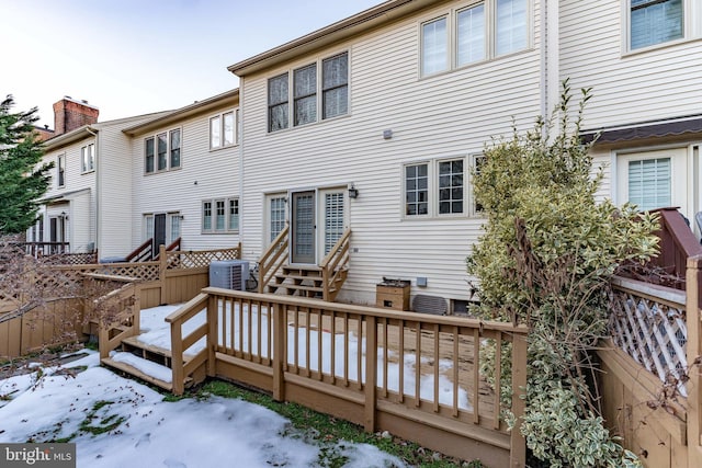 snow covered property featuring central AC unit and a deck