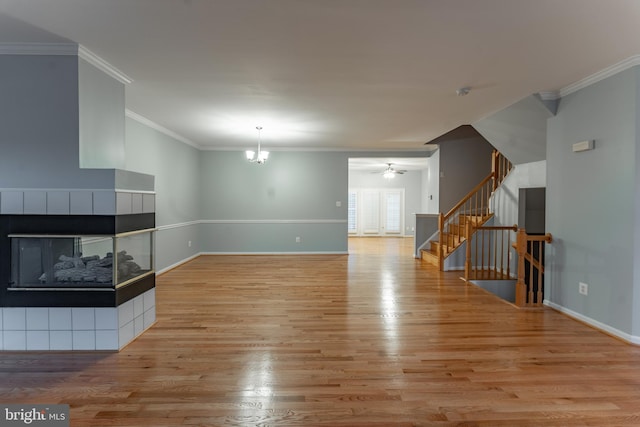 unfurnished living room featuring a multi sided fireplace, ceiling fan with notable chandelier, crown molding, and light hardwood / wood-style floors