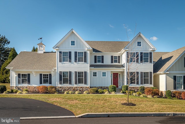 view of front of property with a shingled roof, board and batten siding, and a front yard