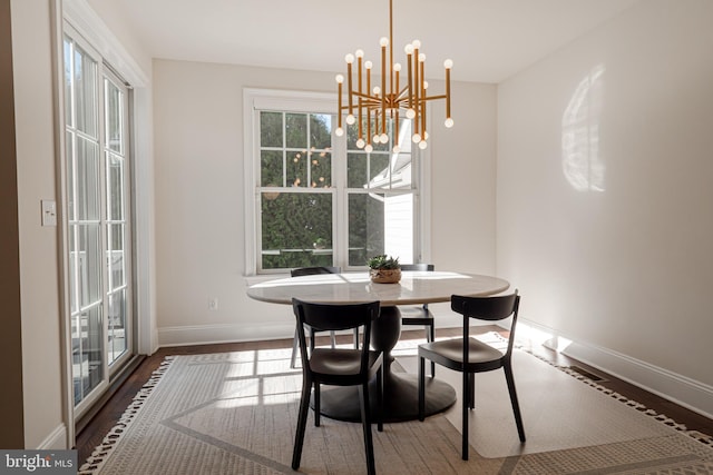 dining space with a notable chandelier, wood finished floors, and baseboards