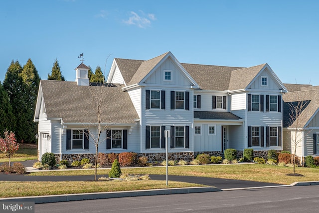 view of front of home featuring a front lawn, board and batten siding, and roof with shingles