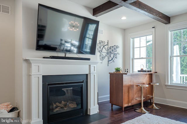 sitting room with visible vents, a fireplace with flush hearth, dark wood-type flooring, beamed ceiling, and baseboards