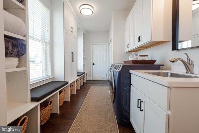 laundry area featuring cabinet space, washing machine and dryer, dark wood finished floors, and a sink