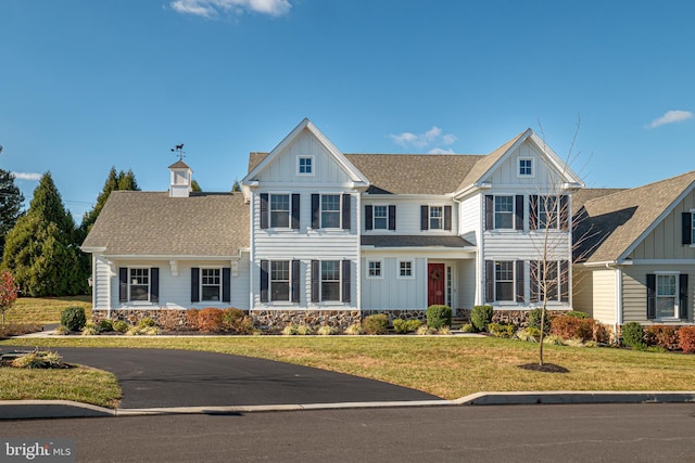 view of front facade with a shingled roof, a front lawn, and board and batten siding