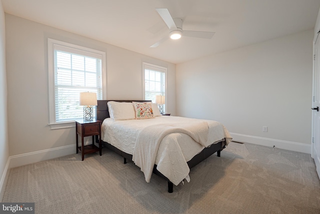 carpeted bedroom with multiple windows, baseboards, and a ceiling fan