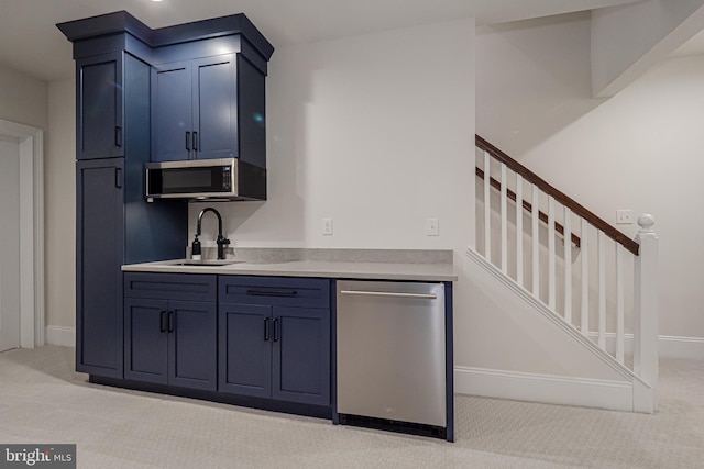 kitchen featuring light colored carpet, stainless steel appliances, a sink, baseboards, and light countertops