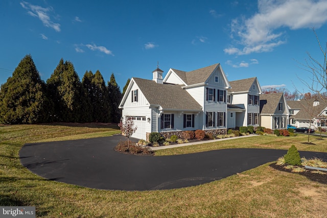 view of front of property featuring a garage, driveway, roof with shingles, board and batten siding, and a front yard