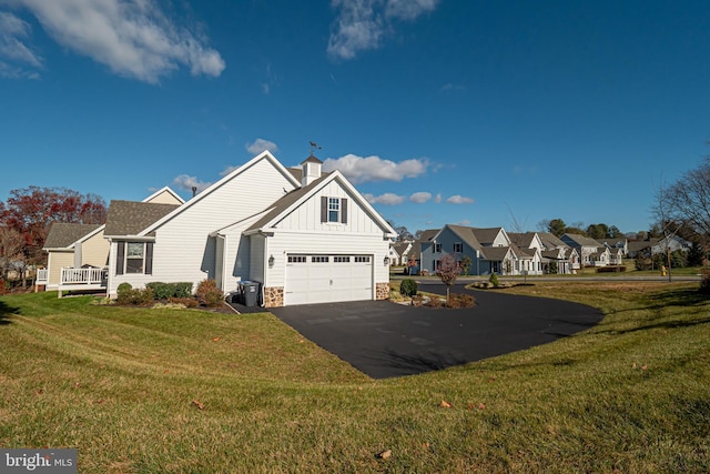 view of front of home featuring driveway, stone siding, a residential view, board and batten siding, and a front yard