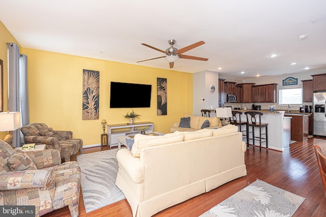 living room with ceiling fan and dark wood-type flooring