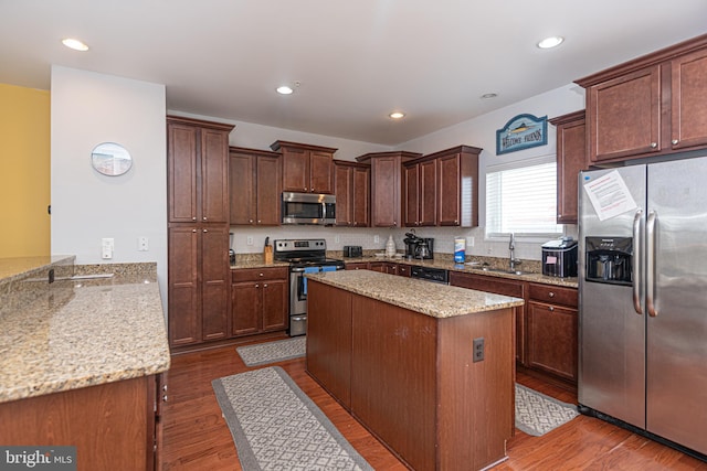 kitchen with sink, wood-type flooring, light stone countertops, and appliances with stainless steel finishes