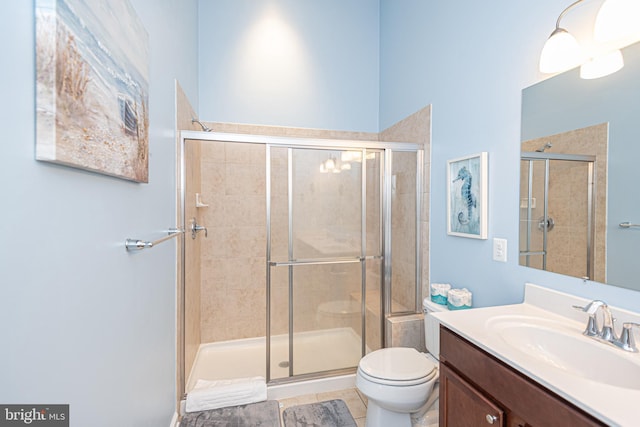 bathroom featuring toilet, vanity, tile patterned flooring, and a shower with shower door