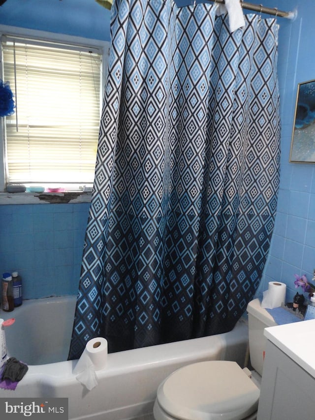 full bathroom with toilet, shower / bathtub combination with curtain, tile walls, and vanity