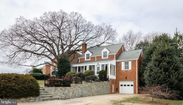 cape cod house featuring concrete driveway, brick siding, a chimney, and an attached garage