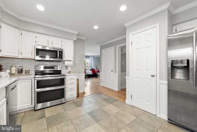 kitchen with crown molding, white cabinets, decorative backsplash, and stainless steel appliances