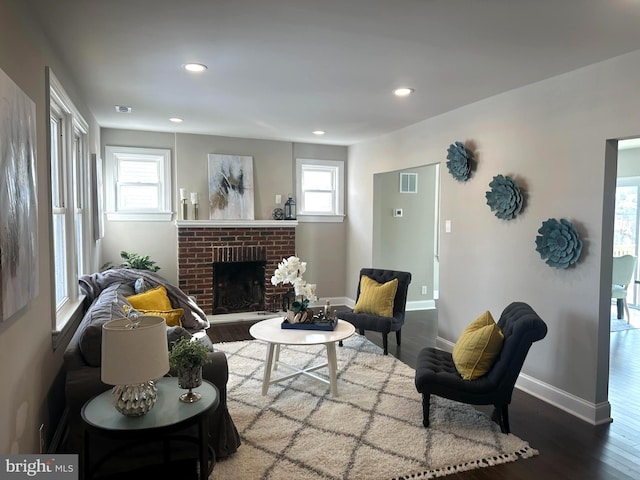 living room featuring a brick fireplace, a wealth of natural light, and hardwood / wood-style flooring