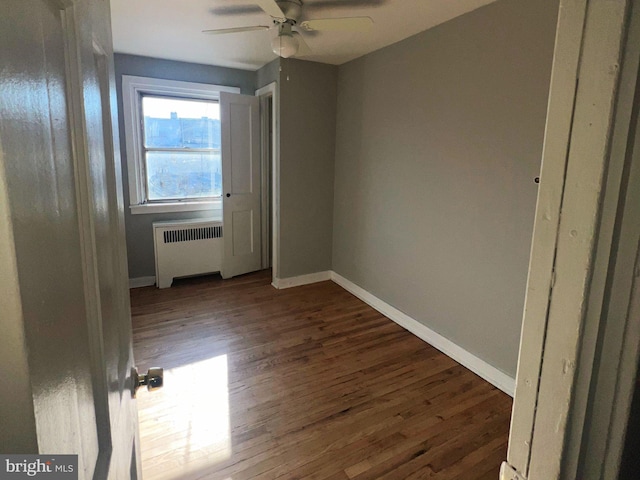 unfurnished room with radiator, ceiling fan, and dark wood-type flooring