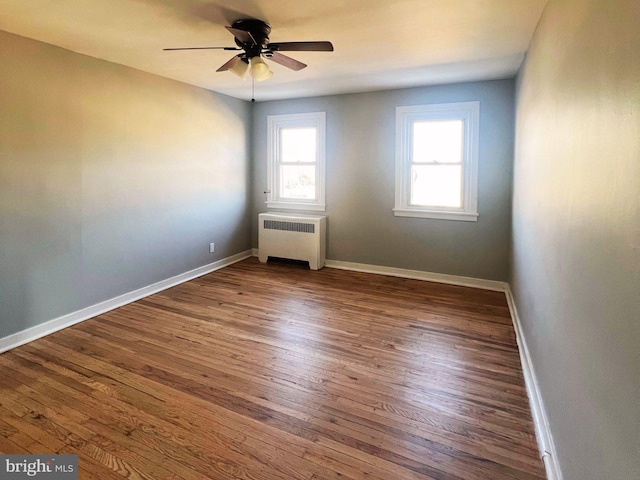 unfurnished room featuring ceiling fan, dark wood-type flooring, and radiator heating unit