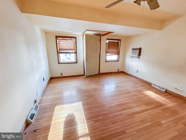 unfurnished room with a wall mounted AC, ceiling fan, and light hardwood / wood-style floors