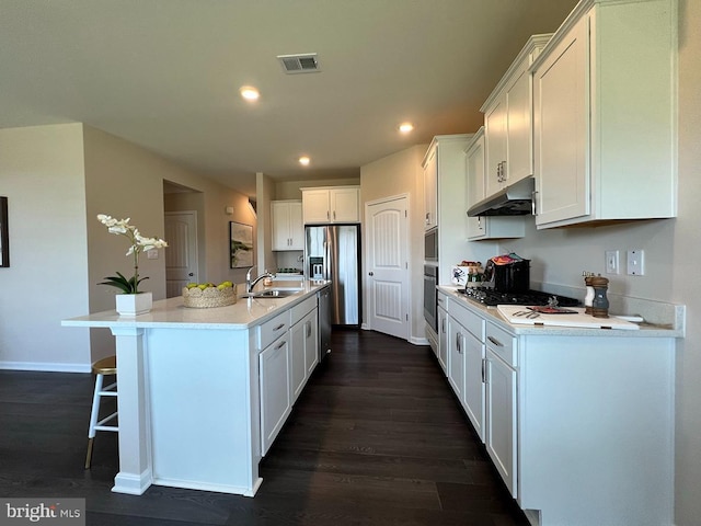 kitchen with dark wood-type flooring, an island with sink, white cabinets, appliances with stainless steel finishes, and sink