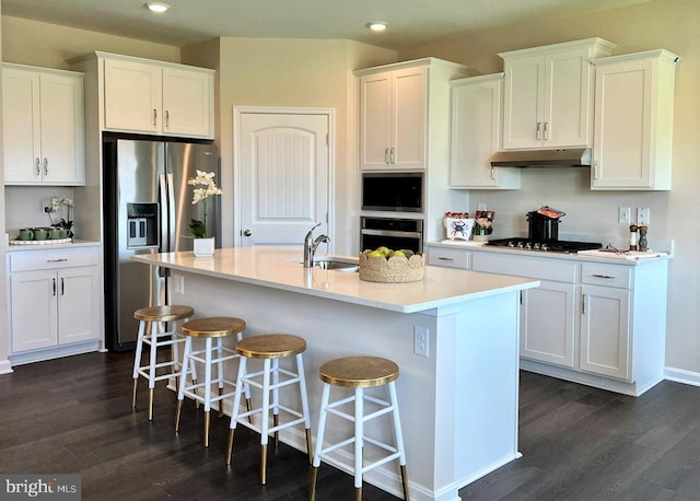 kitchen featuring stainless steel appliances, sink, white cabinets, an island with sink, and dark hardwood / wood-style flooring