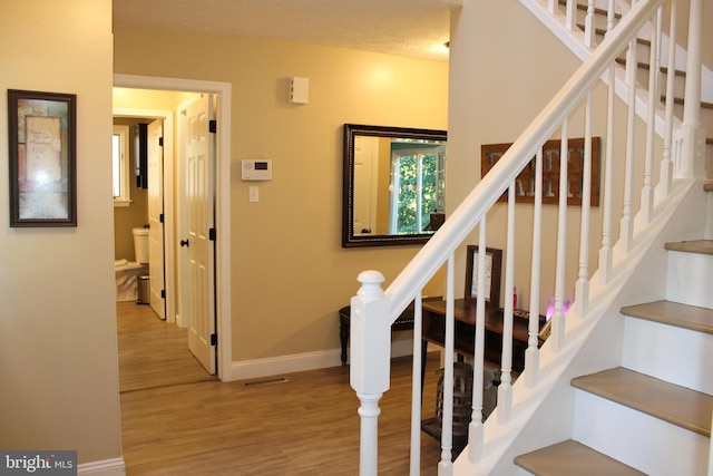 stairs with a textured ceiling and hardwood / wood-style floors