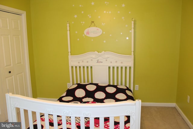 carpeted bedroom with a closet and a nursery area