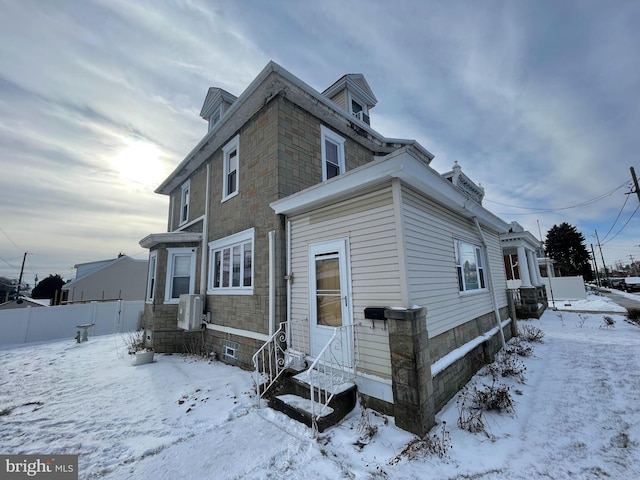 snow covered rear of property with entry steps and fence