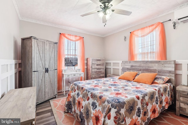 bedroom with a wall unit AC, a ceiling fan, crown molding, and wood finished floors