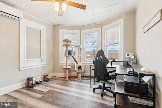 office space with a wall unit AC, ornamental molding, ceiling fan, wood finished floors, and baseboards