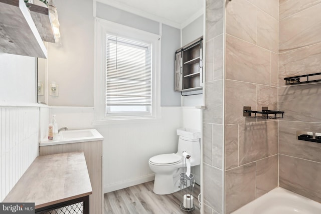 bathroom featuring a shower, toilet, ornamental molding, wood finished floors, and vanity