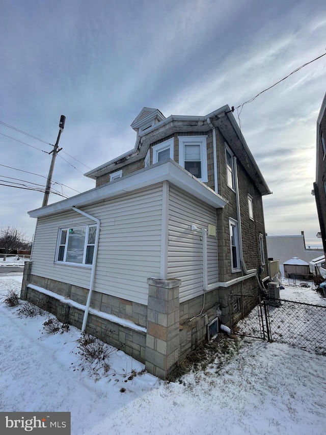 view of snow covered exterior with central air condition unit and fence