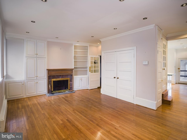 unfurnished living room with light hardwood / wood-style flooring, ornamental molding, a brick fireplace, built in shelves, and a baseboard radiator