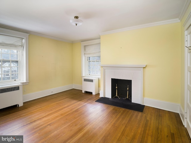 unfurnished living room featuring crown molding, wood-type flooring, radiator, and a fireplace