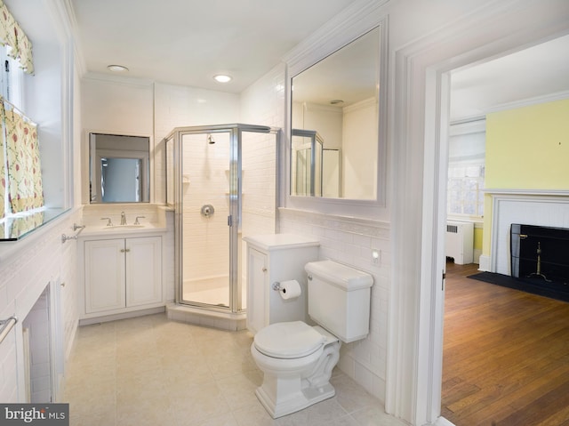 bathroom featuring a shower with door, radiator heating unit, vanity, ornamental molding, and toilet