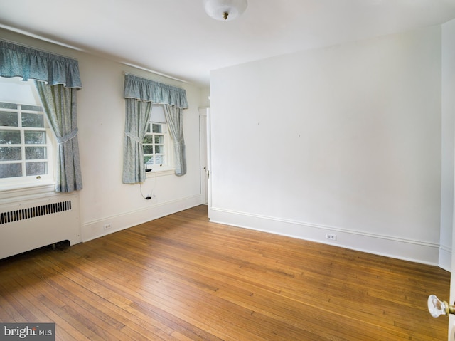 unfurnished room with hardwood / wood-style flooring and radiator heating unit