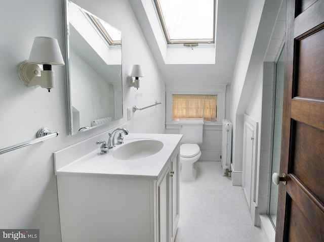 bathroom featuring a skylight, radiator heating unit, vanity, tile patterned floors, and toilet