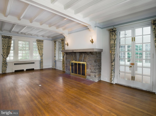 unfurnished living room with a stone fireplace, radiator heating unit, wood-type flooring, plenty of natural light, and french doors