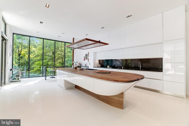 interior space featuring floor to ceiling windows, white cabinets, and a kitchen bar