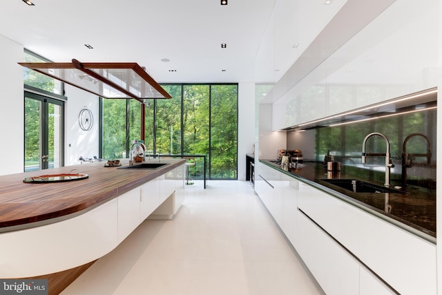 kitchen featuring expansive windows, white cabinets, butcher block countertops, and sink