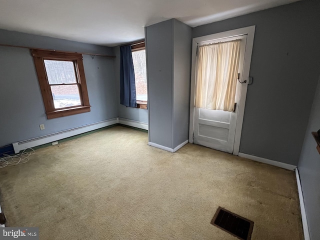 carpeted empty room with a baseboard heating unit