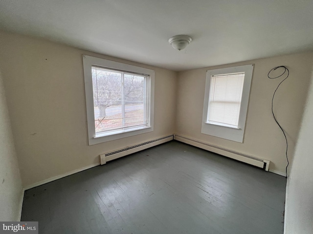 spare room featuring a baseboard heating unit and hardwood / wood-style floors