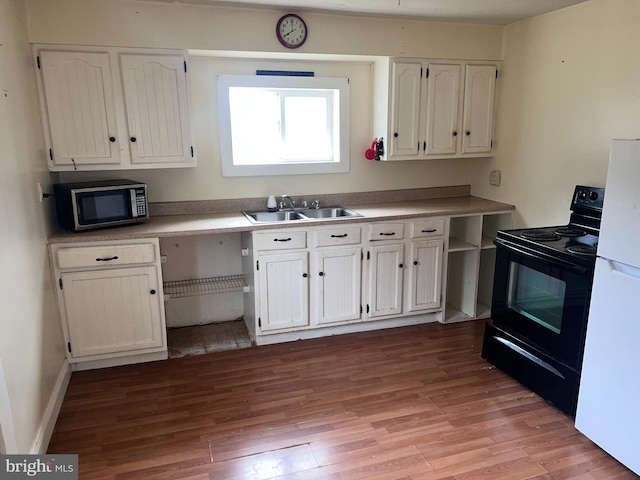 kitchen featuring white fridge, black range with electric stovetop, light wood-type flooring, sink, and white cabinetry