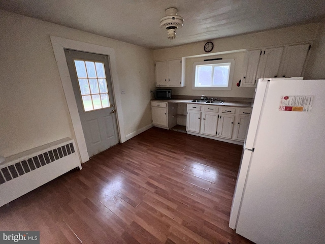 kitchen with white refrigerator, radiator heating unit, a wealth of natural light, sink, and white cabinetry