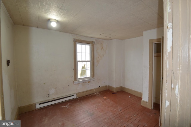 empty room with a baseboard heating unit and hardwood / wood-style floors