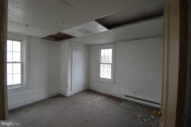 interior space with a healthy amount of sunlight, a paneled ceiling, and a baseboard heating unit