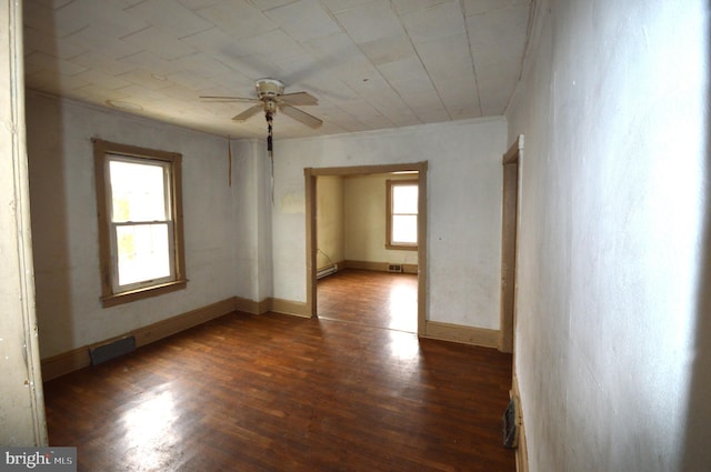 unfurnished room with baseboard heating, ceiling fan, and dark wood-type flooring