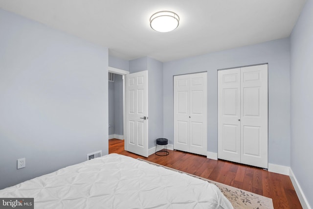 bedroom featuring two closets and hardwood / wood-style flooring